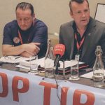 Two men at a table for a a political event in Tipperary with a microphone pointed at Brendan Ogle