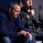 Brendan Ogle speaking and Richard Boyd Barratt looking downwards listening