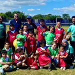 Brendan supporting young football team group shot of people of colour in the sunshine on a football pitch