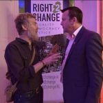 Glen Hansard singer, man with ginger hair and a beard dressed casually, songwriter talking animatedly to Brendan Ogle, looking interested and serious in formal office attire. in front of a Right2Change banner