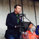 Addressing crowd on May Day International Workers Day from a podium brendan speaking with a woman looking on