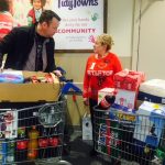 Brendan Ogle and a blonde woman from Tidy Towns with trolleys full of food at a food collection point